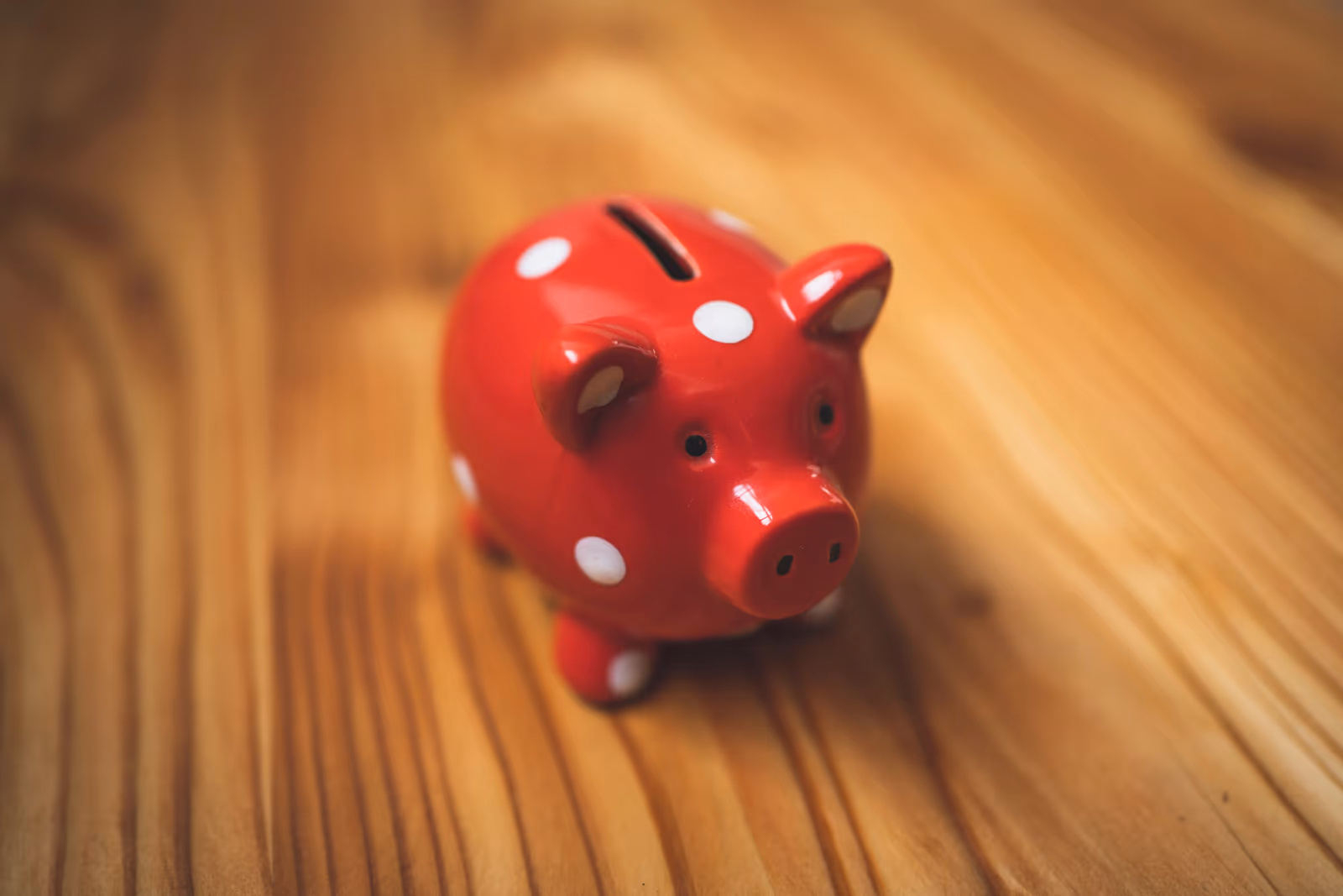 red polka-dot piggy bank sitting on a wooden surface