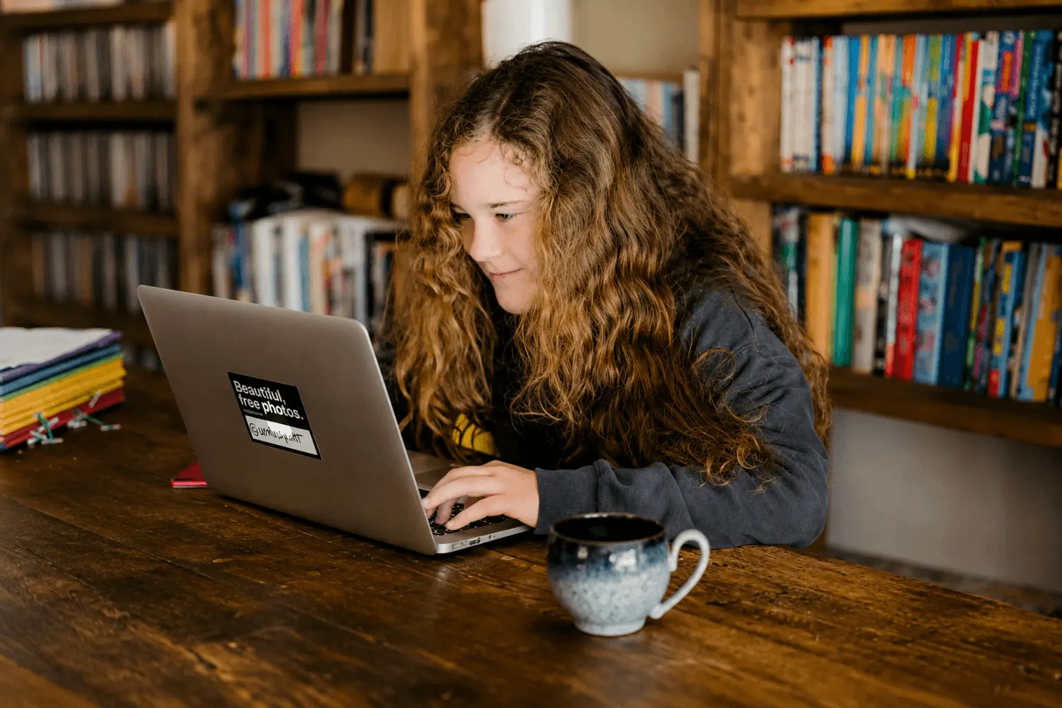Girl typing on a laptop at a library table
