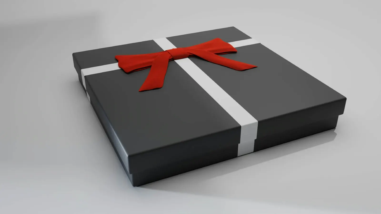 Black gift box tied with a white ribbon and red bow