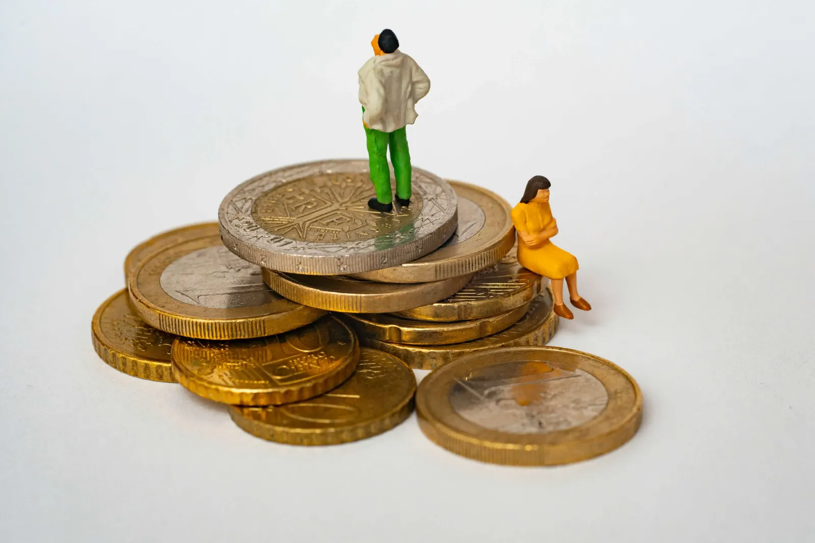 Miniature figures standing and sitting atop stacked euro coins