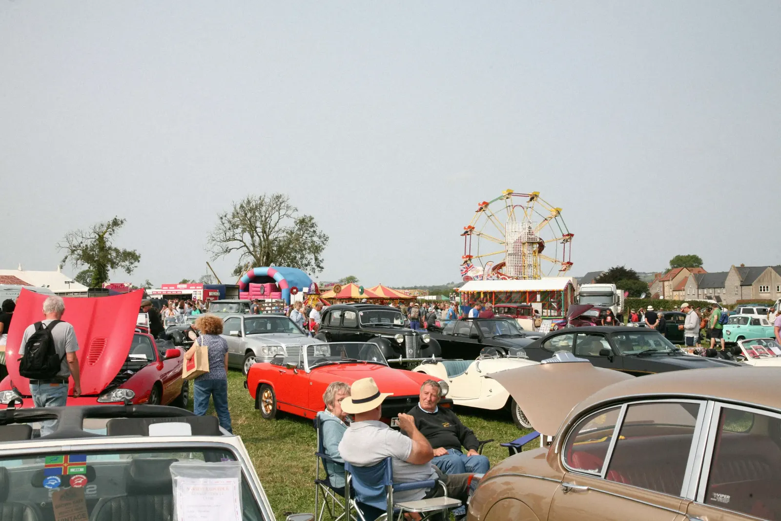 Classic car show with a Ferris wheel and crowd in the background