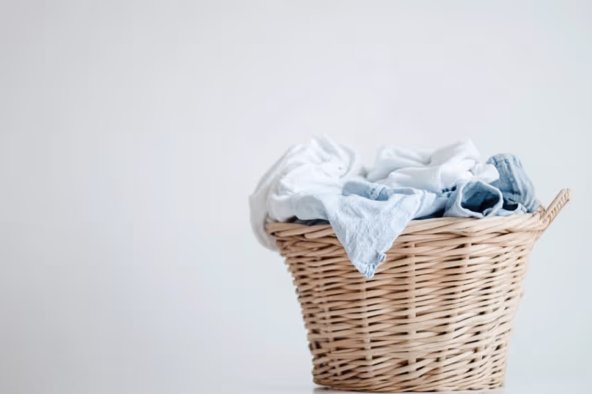 Woven wicker basket filled with folded white and blue linens