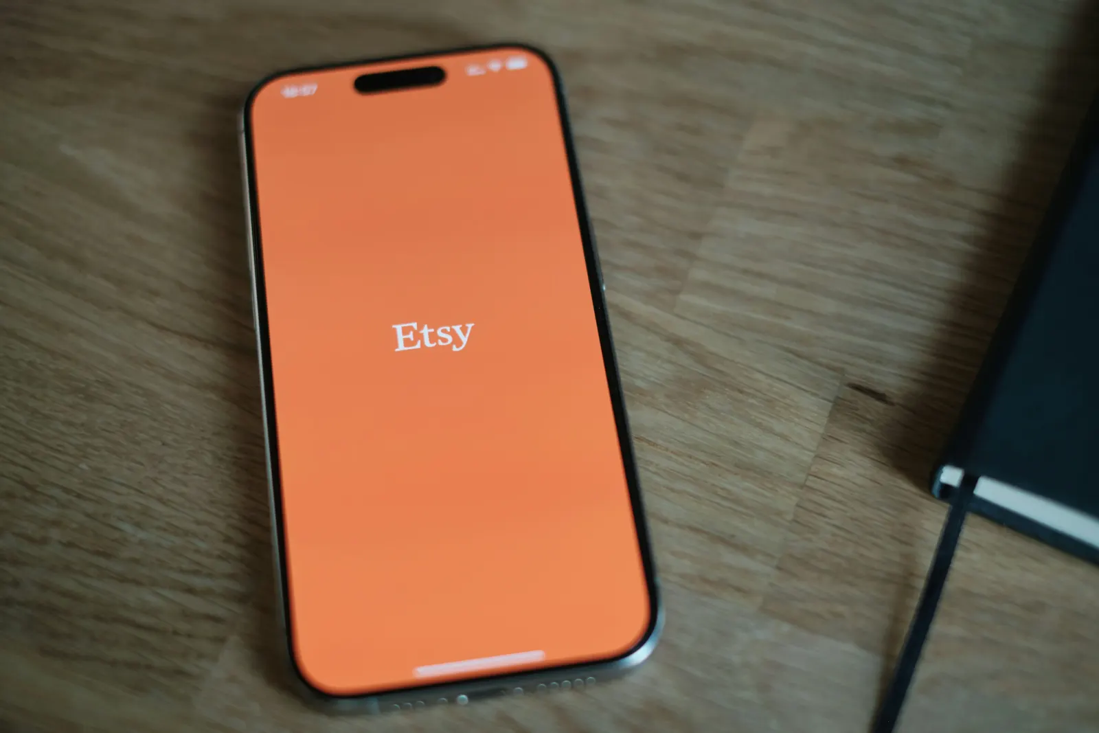 Smartphone showing the Etsy app logo on a wood table