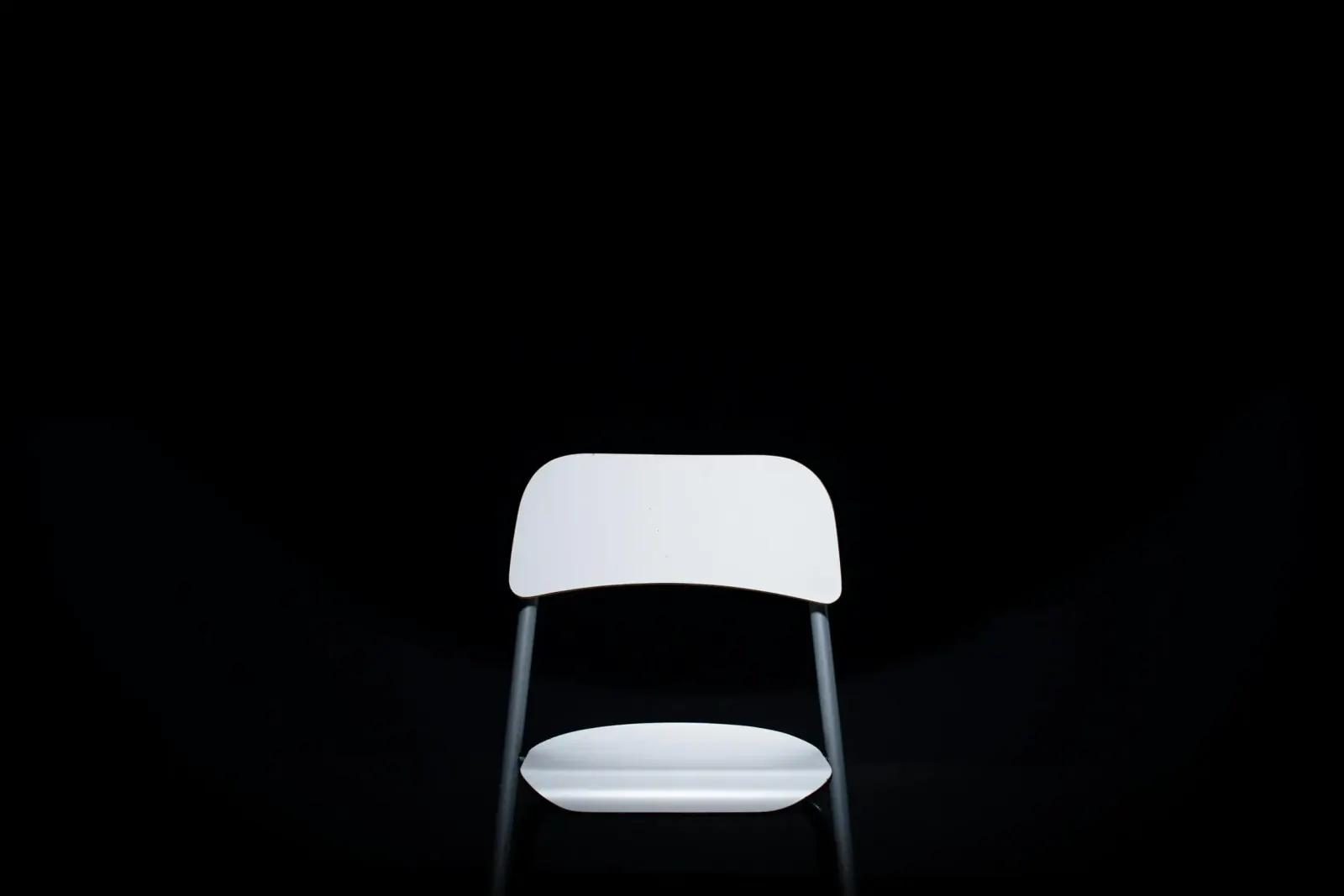 Single white chair spotlighted against a black background