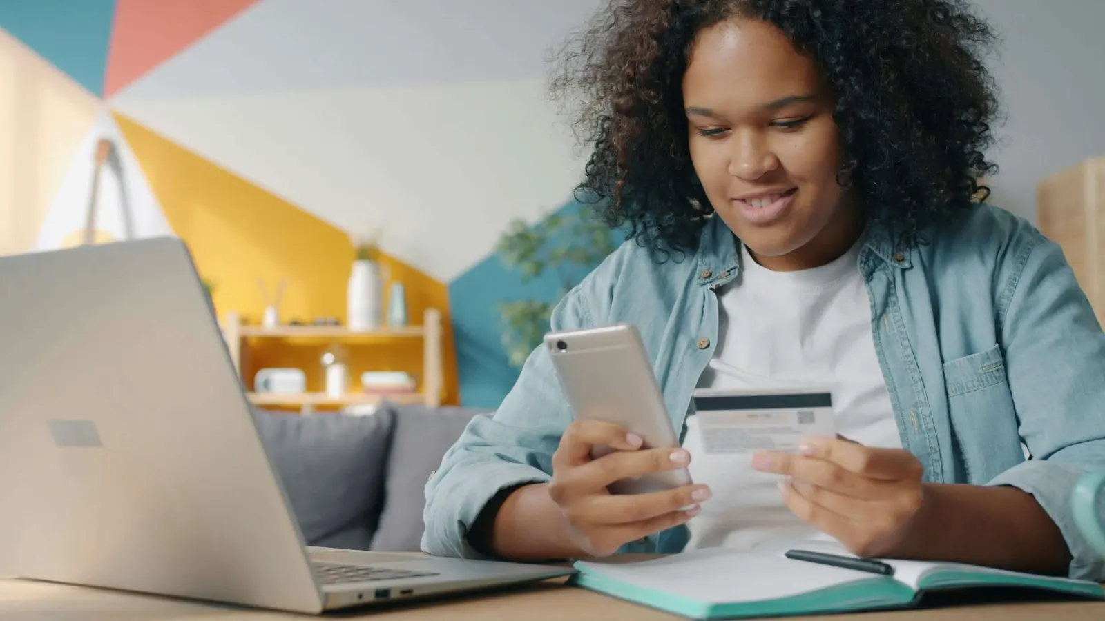 Afroamerican girl holds a debit card and a phone