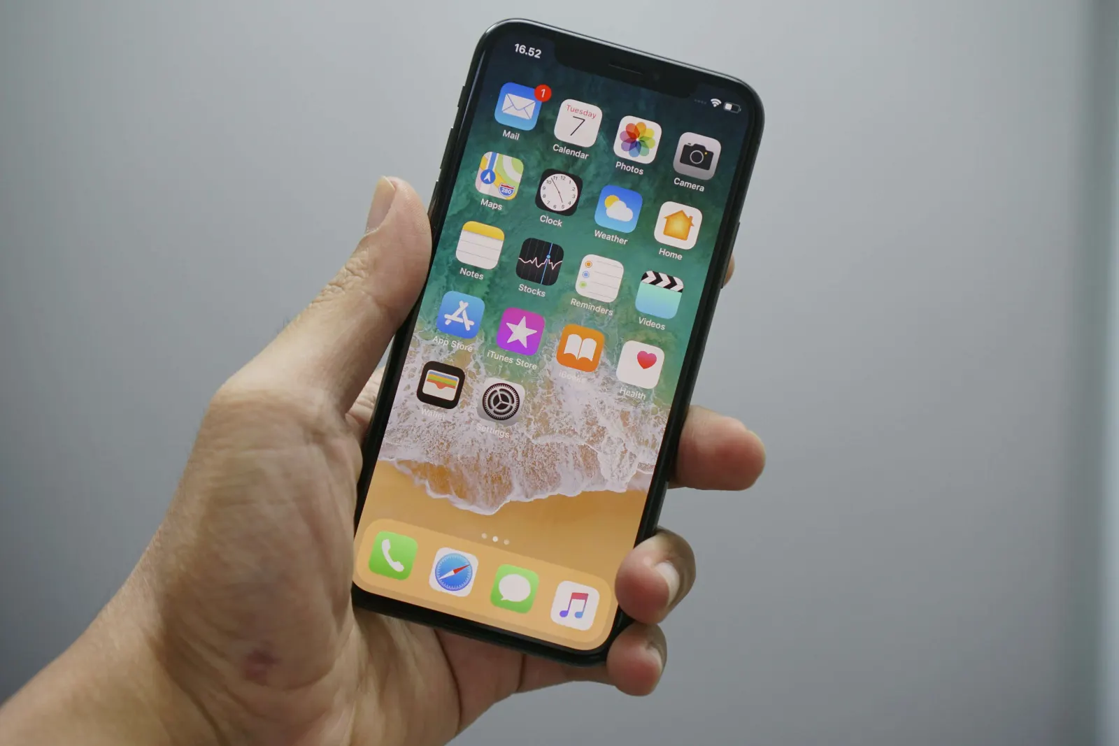 Hand holding an iPhone displaying its home screen apps