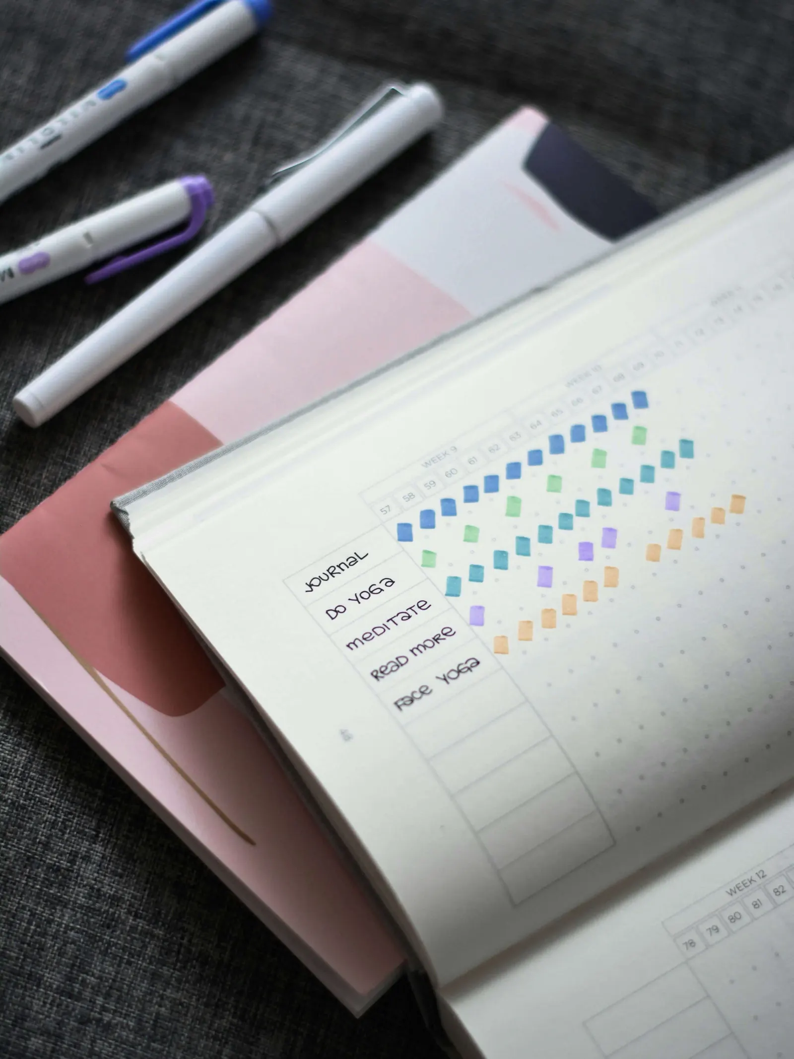 Habit-tracker journal page with colored squares and markers nearby
