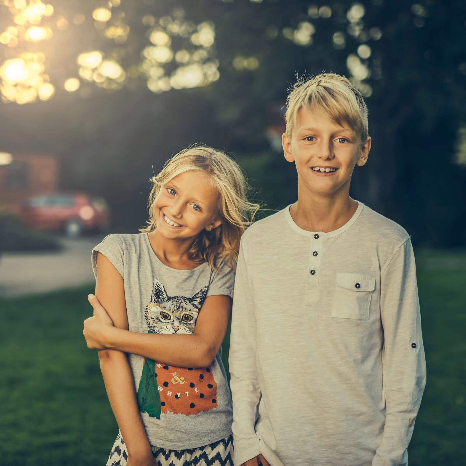 Smiling blonde girl and boy standing together outdoors at dusk