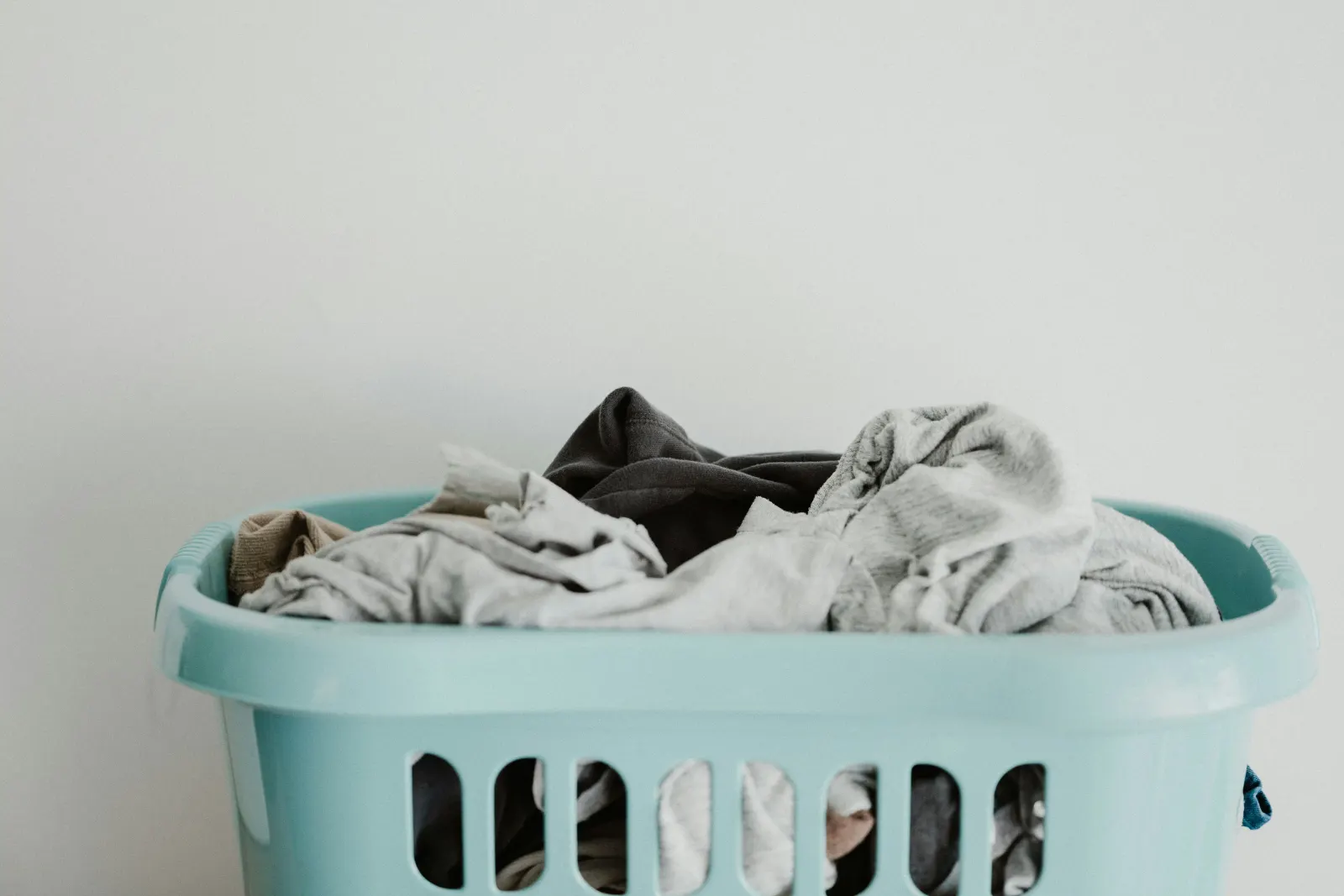 Mint green laundry basket piled with folded clothes