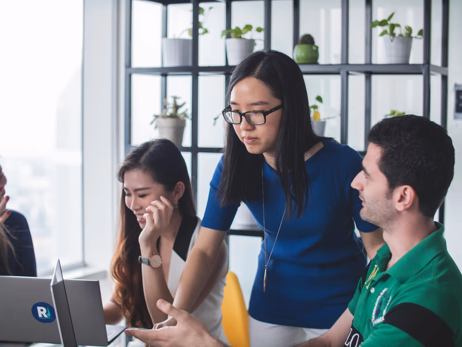 Group of young professionals looking together at a laptop in an office
