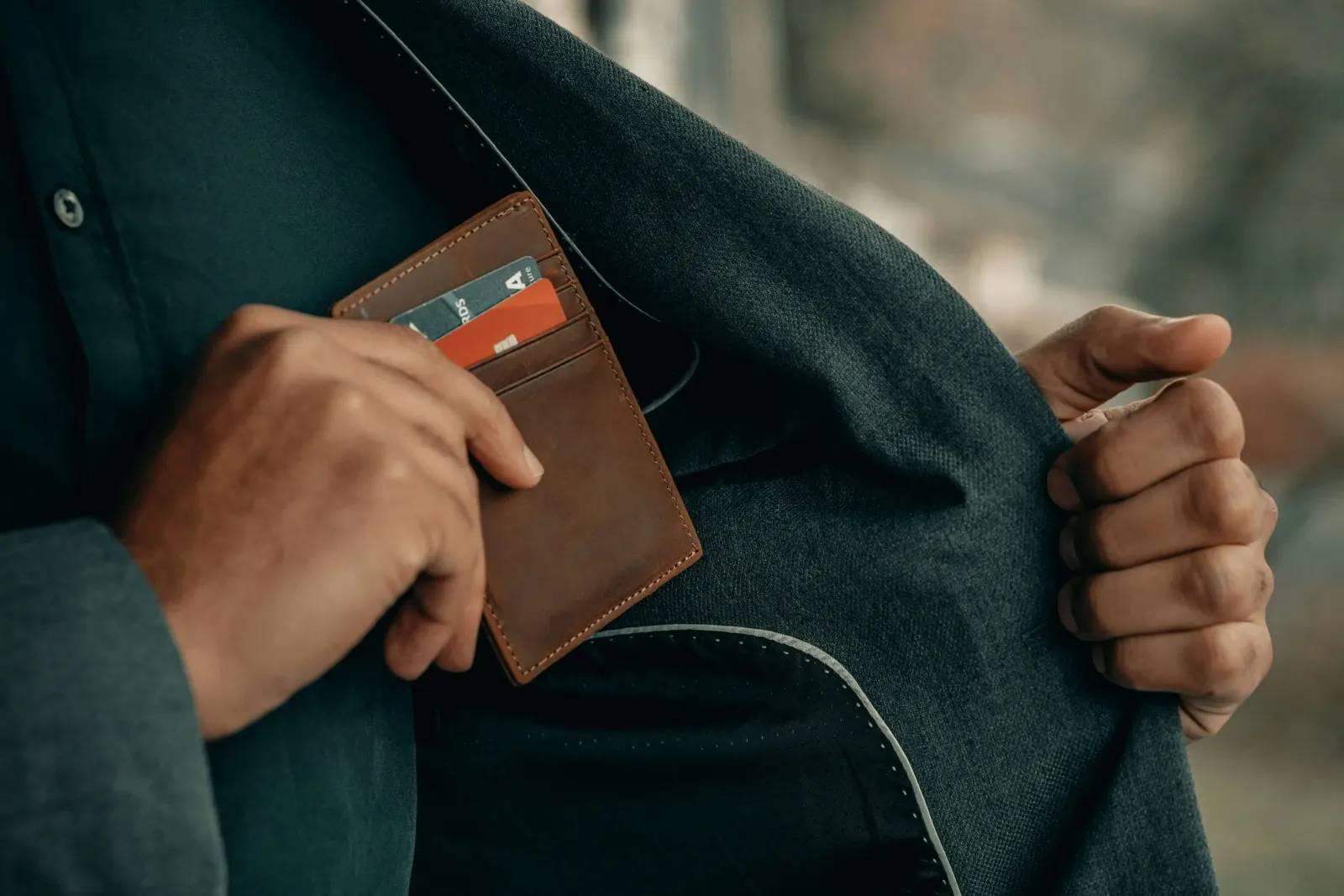 Hand tucking a wallet with cards into a suit jacket pocket