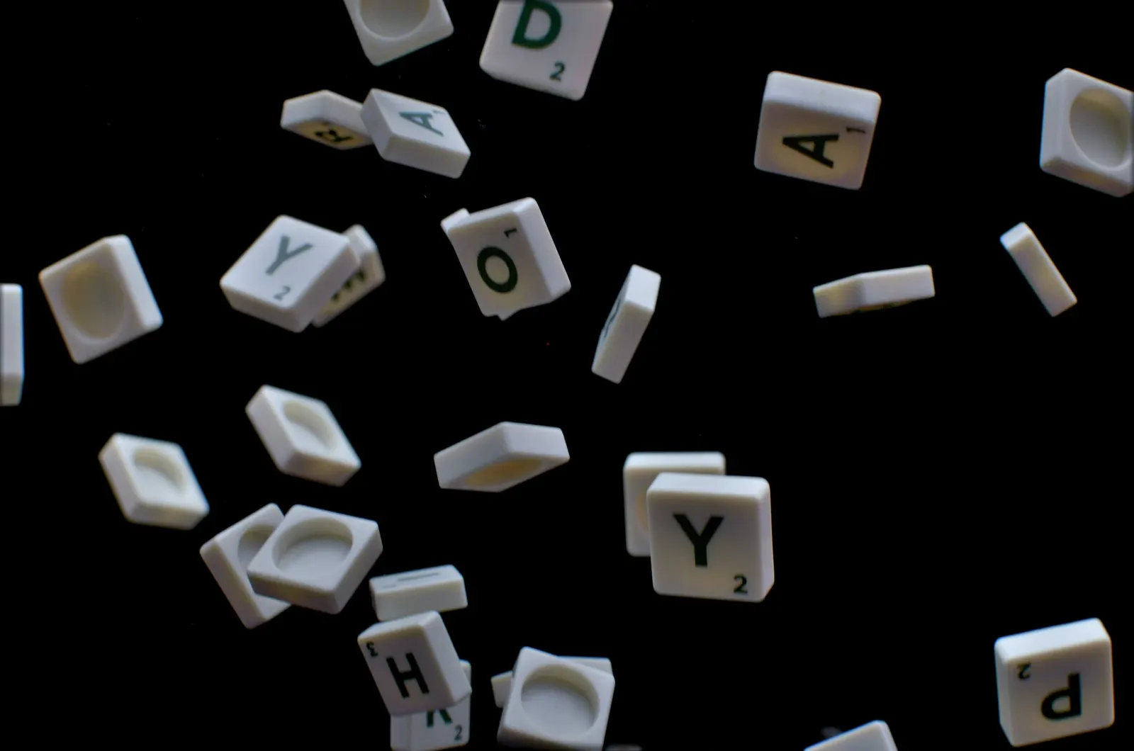 Scrabble letter tiles scattered on a black background