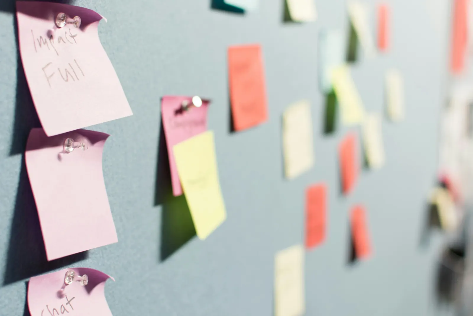 Pink and yellow sticky notes reading 'Impact Full' on a board