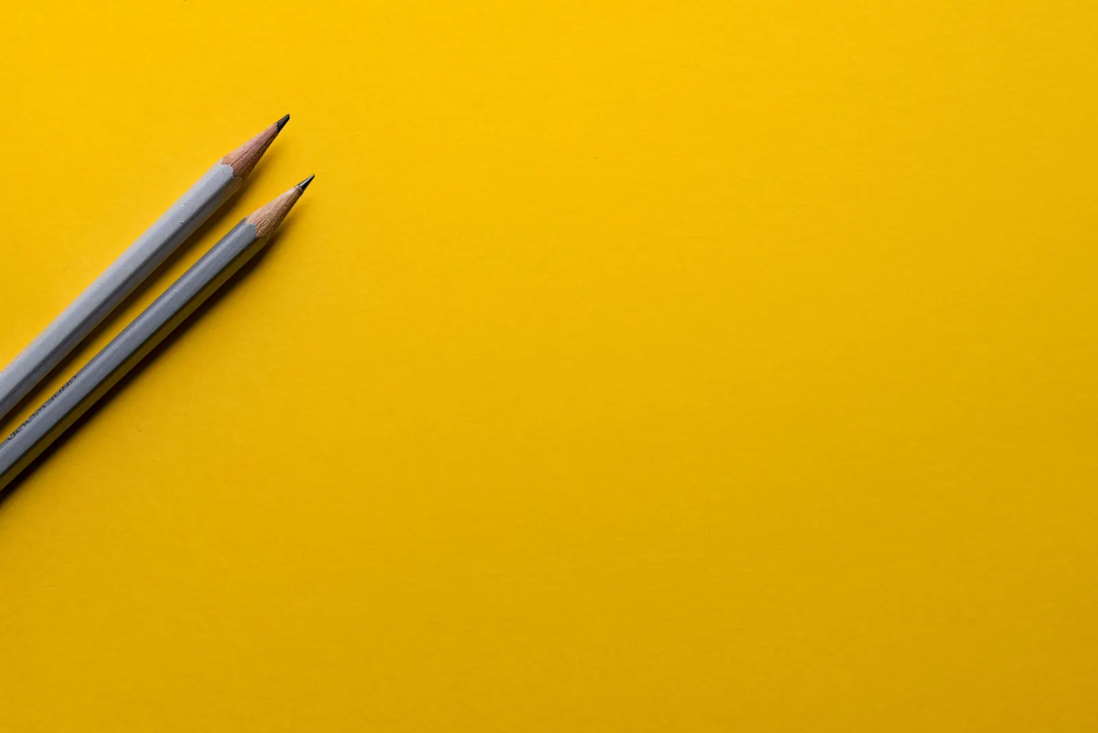 Two sharpened pencils lying on a yellow background