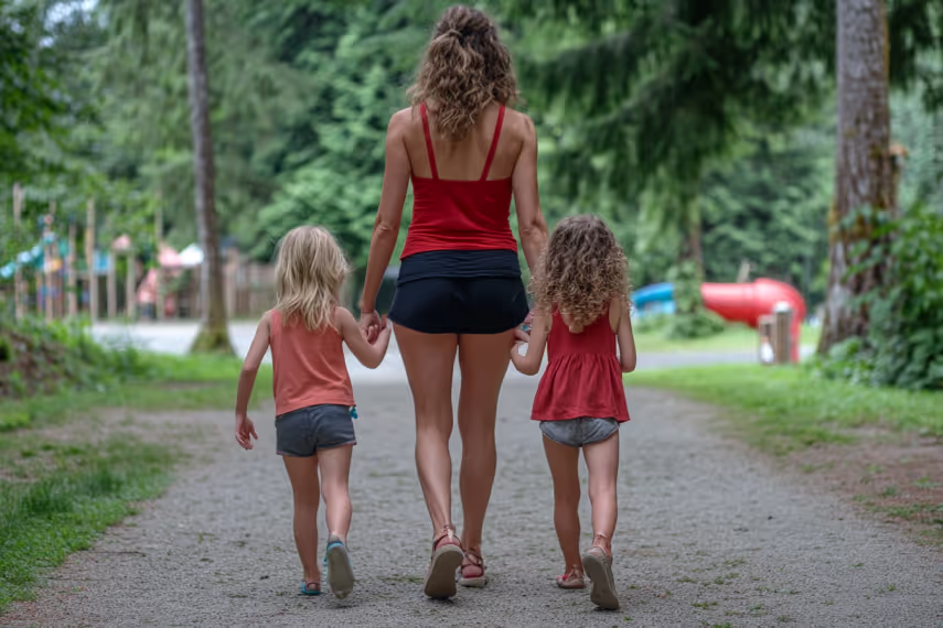 Woman walking hand in hand with two girls on a path