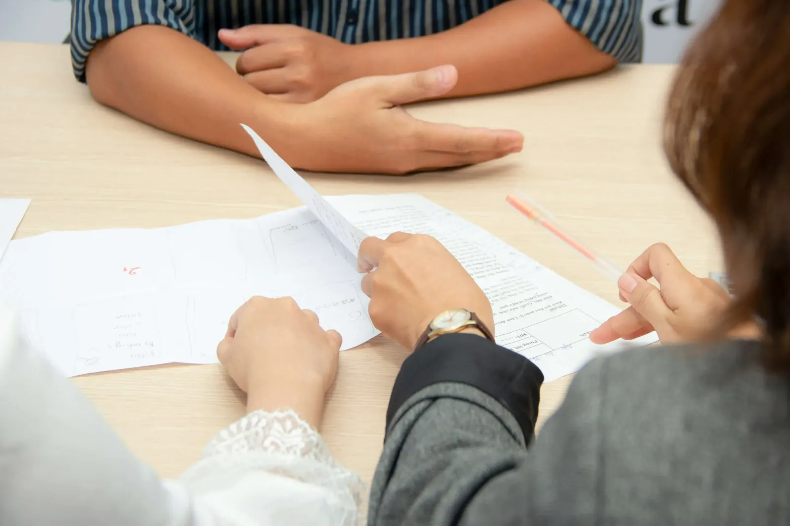 Hands pointing at documents spread on a table during a meeting